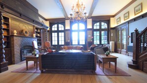 A spacious living room with a fireplace, large windows, and a chandelier. - Spa Grand Wellness Villa (Spa)