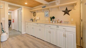 A kitchen with white cabinets, a wooden ceiling, and a countertop with various items.