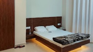 Un dormitorio con cabecera de madera, cama con ropa blanca y una manta de diseño.