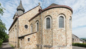 Eine historische Steinkirche mit einem Glockenturm und Rundbogenfenstern.