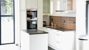 A modern kitchen with white cabinetry, a double oven, a stainless steel range hood, and a tiled backsplash. - Farmhouse Retreat, Fernelmont (Forville)