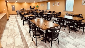 Uma ampla sala de jantar com várias mesas e cadeiras, um balcão de recepção e um balcão.