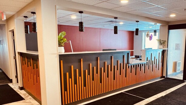 A reception area with a modern design, featuring a reception desk, a plant, and a patterned floor.