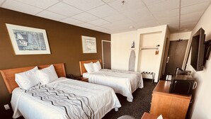 A hotel room with two beds, a desk, a television, and a microwave.