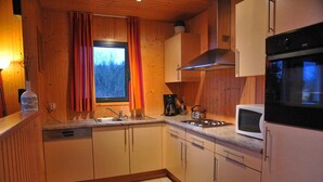 Une cuisine de taille réduite, dotée de meubles en bois, d’un four à micro-ondes et d’un évier.