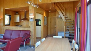L’intérieur d’une cabane en bois comprend un coin repas, une cuisine et un escalier.