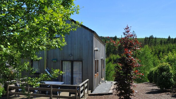 Un bâtiment de style rustique doté d’une terrasse en bois et d’un espace extérieur aménagé pour s’asseoir.