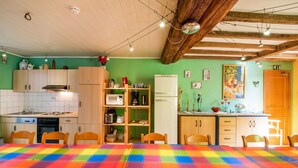 Una cucina accogliente con mobili in legno, un tavolo da pranzo con tovaglia colorata e una parete verde decorata con opere d'arte.