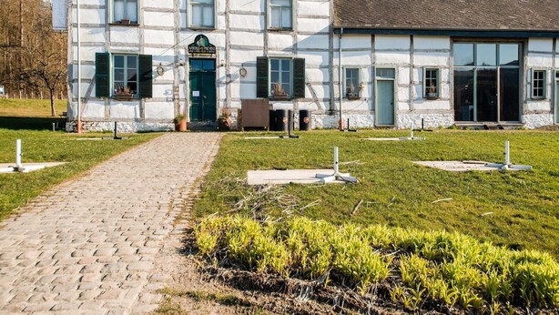 Un edificio tradizionale a graticcio con un ingresso lastricato e un prato verde.
