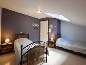 A bedroom with two beds, a skylight, a door, and a wall-mounted mirror.