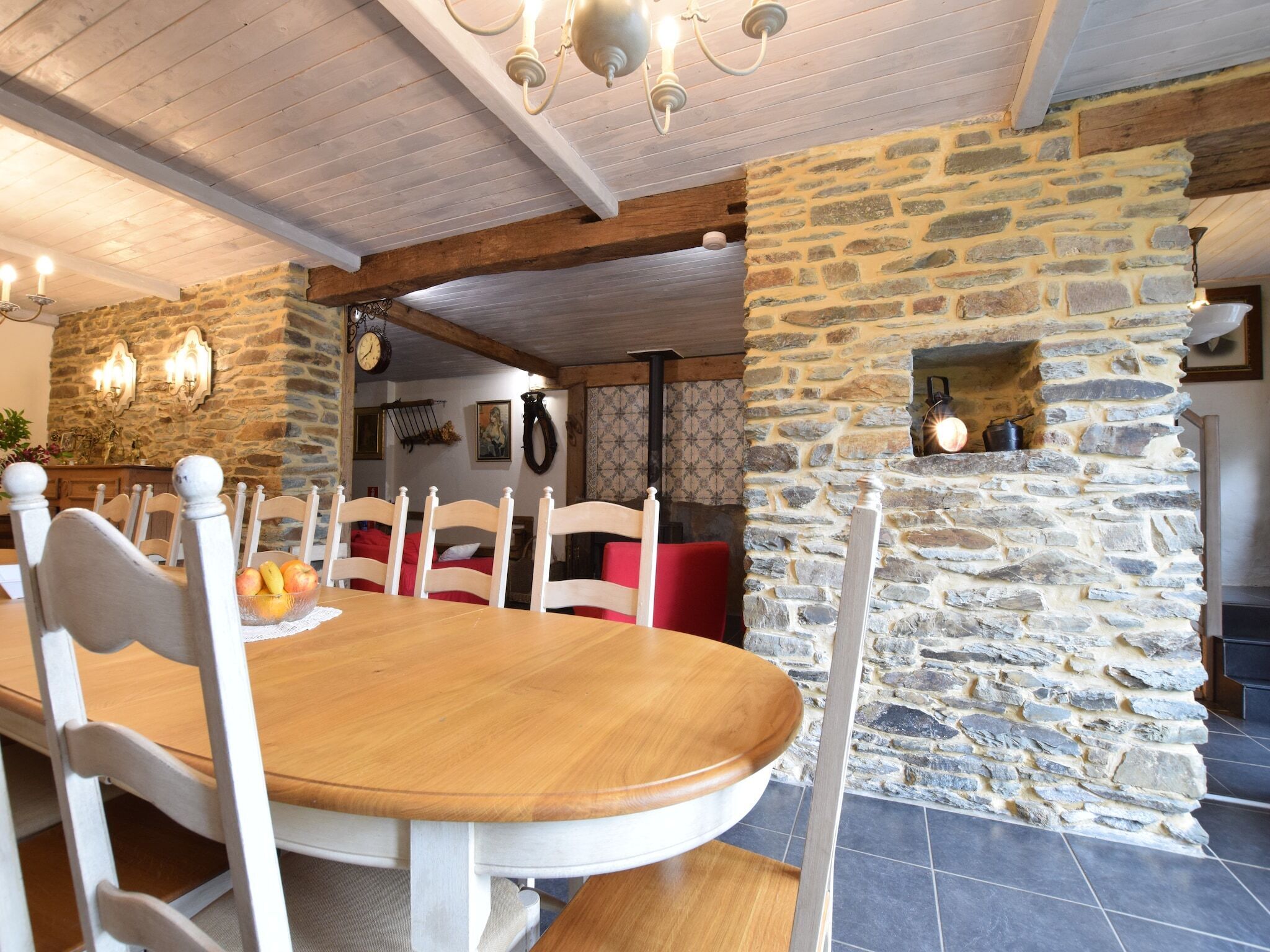 A dining area with a wooden table and white chairs, stone walls, and a stone fireplace.