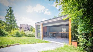 Un espacio moderno para comer al aire libre con cerramiento de vidrio, una mesa y sillas de patio.