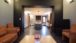 Una sala de estar moderna con una mesa de centro, sofás, un televisor y un comedor al fondo.
