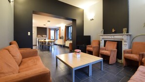 Una sala de estar moderna con chimenea, sofás naranja, comedor y televisor.