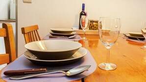 Mesa de comedor preparada con platos, tazones, una botella de vino y copas.