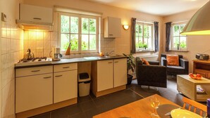 Een compact keuken met een eethoek, inclusief een fornuis, spoelbak en een raam met gordijnen.