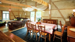 Un intérieur rustique en bois, avec un coin repas, un canapé et une table dressée pour quatre personnes.