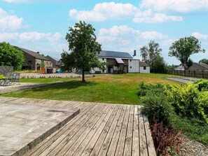 A modern house with a solar panel roof, surrounded by a well-maintained lawn and a wooden deck.