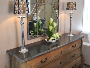 A wooden dresser with drawers, a mirror, and two lamps with patterned shades. - Cozy Cottage for 8 Guests (Le Bizet)