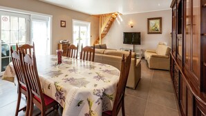 Ein geräumiges Wohnzimmer mit Essbereich, einer Sofagarnitur, einem Fernseher und einer Treppe.