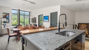 Une cuisine moderne dotée d’un plan de travail en granit, d’un évier encastré et d’un coin repas avec des chaises et une table.
