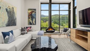 Un salon moderne avec une cheminée, de grandes fenêtres et un canapé confortable.
