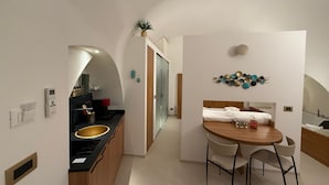 Una cucina moderna con isola centrale, zona pranzo con tavolo e sedie in legno, e composizione decorativa di piatti a parete.