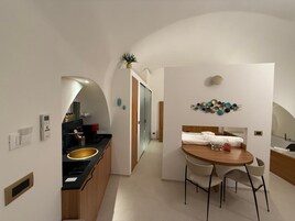 Una cucina moderna con isola centrale, zona pranzo con tavolo e sedie in legno, e composizione decorativa di piatti a parete.
