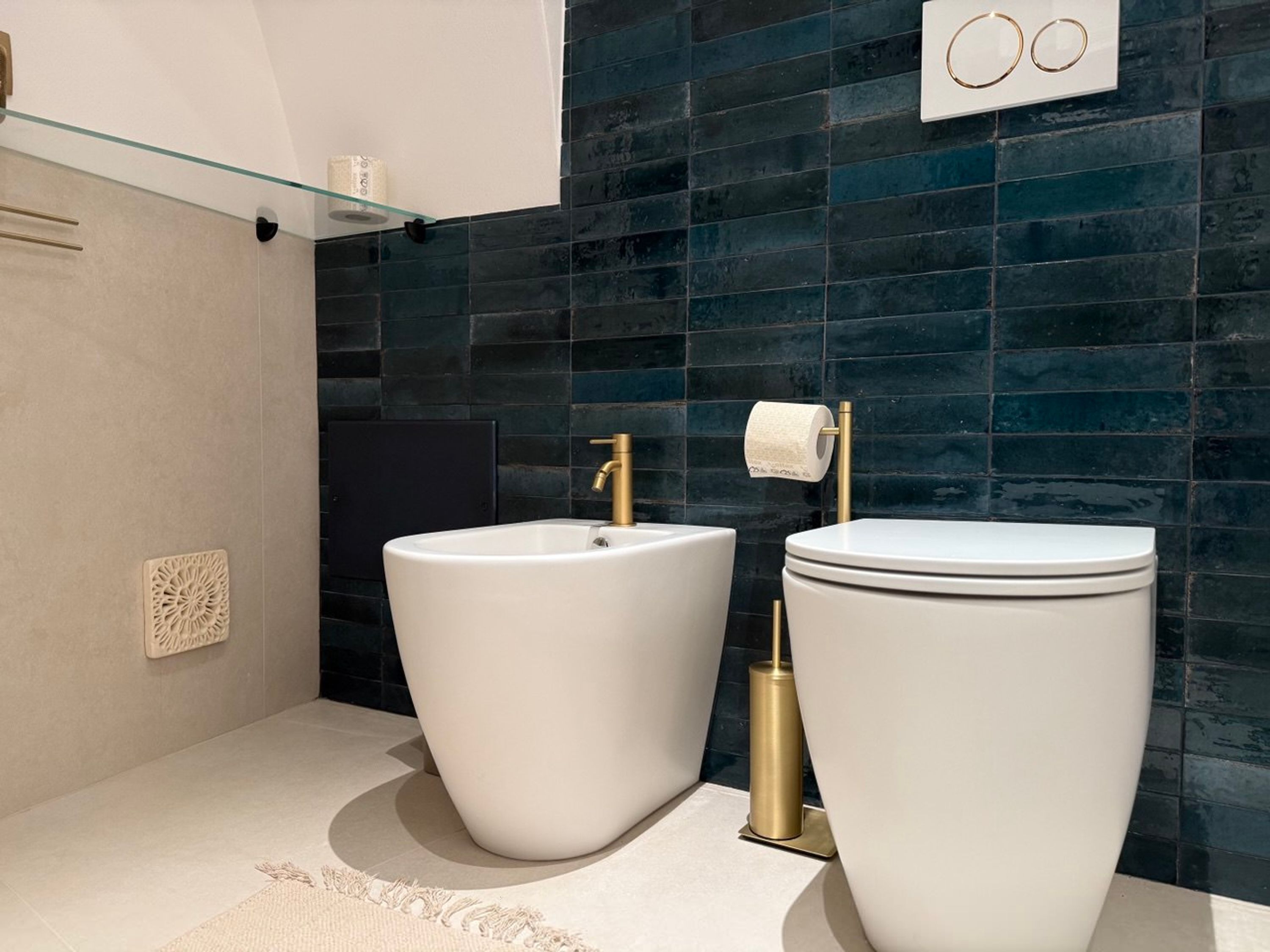 Une salle de bain moderne avec deux lavabos blancs, un robinet doré et des toilettes.