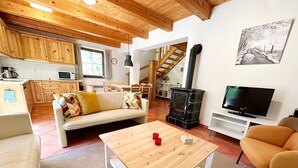 A cozy living room with a wooden coffee table, a sofa, and a television. - Mountains Family Retreat (Rudník)