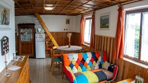 A cozy room with a wooden ceiling, a colorful sofa, a dining table, and a kitchen area with a refrigerator and cabinets. - Outdoor Adventure & Relaxation (Svinařov Slabce)