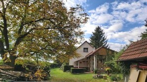 A rustic house with a sloped roof, surrounded by a well-maintained garden and a wooden fence. - Outdoor Adventure & Relaxation (Svinařov Slabce)
