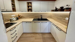A compact kitchen with white cabinets, a black sink, and wooden countertops. - Outdoor Adventure & Relaxation (Svinařov Slabce)