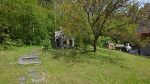 A stone structure with a roof, surrounded by grass and trees.