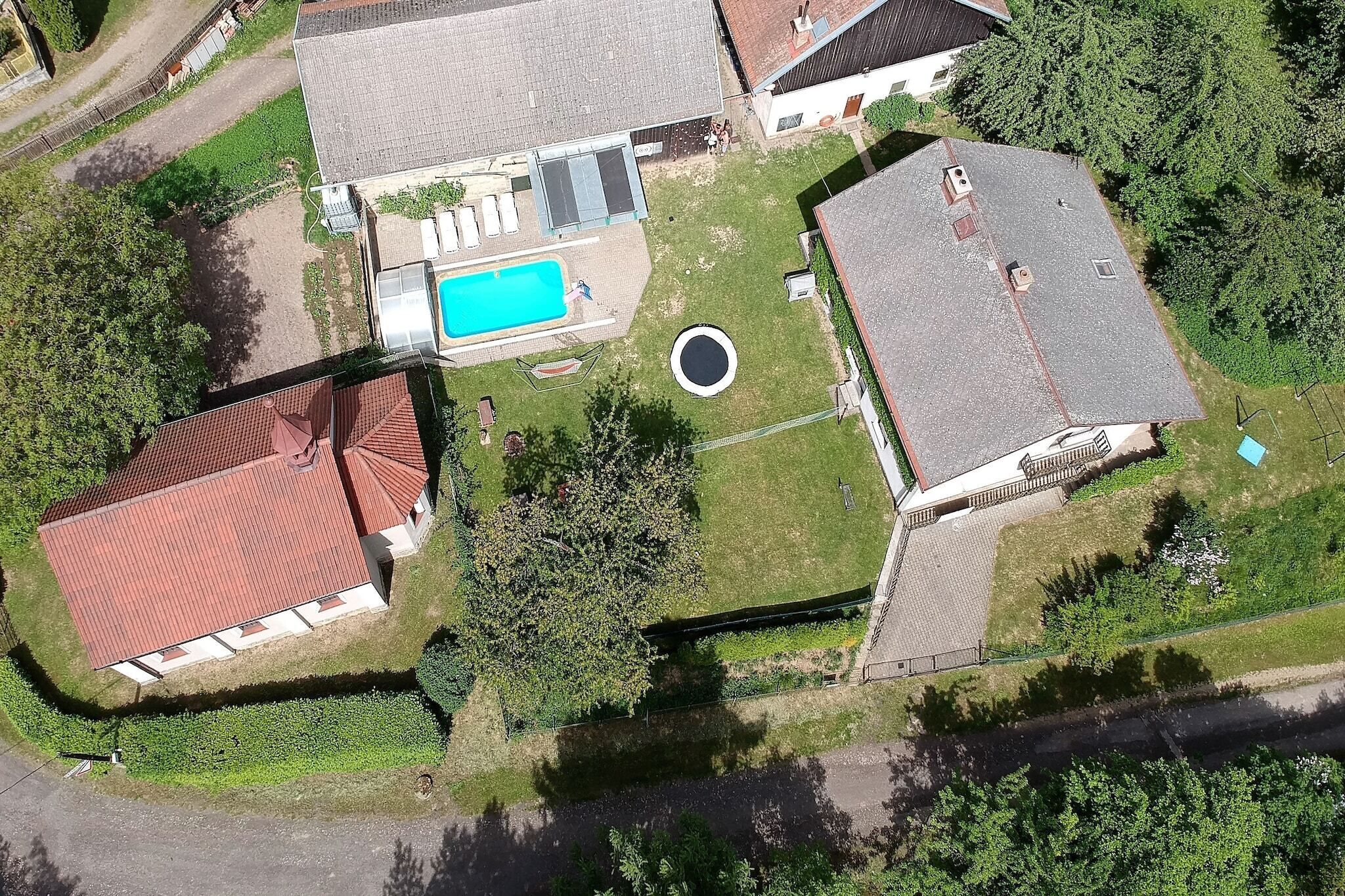 Luchtbeeld van een woonhuis met zwembad, omheinde tuin en een cirkelvormig oprit.