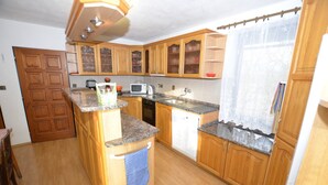 A kitchen with wooden cabinets, a granite countertop, a microwave, a sink, and a dishwasher. - Villa in Zelenecká Lhota with Private Pool (Liban)