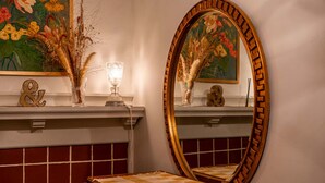 Un baño con un espejo grande, un florero con plantas secas y un cuadro sobre el espejo.