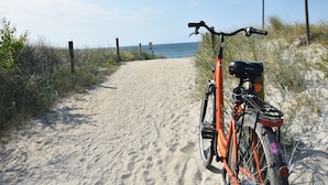 A sandy path leading to the beach with a bicycle parked on the side. - Ferienwohnung Im Heumond in Buschhagen (Buschenhagen)
