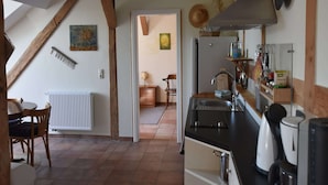 A kitchen with a wooden ceiling, a refrigerator, a sink, and a coffee maker. - Ferienwohnung Im Heumond in Buschhagen (Buschenhagen)