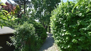A cobblestone path flanked by lush greenery and a wooden structure. - Ferienwohnung Im Heumond in Buschhagen (Buschenhagen)
