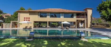 Una piscina al aire libre, sombrillas, sillones reclinables de piscina