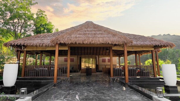 A thatched-roof pavilion with a marble floor, surrounded by greenery and a mountainous backdrop. - Tree of Life Amara Resorts & Spa Udaipur (Udaipur)