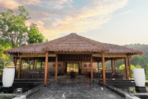 A thatched-roof pavilion with a marble floor, surrounded by greenery and a mountainous backdrop. - Tree of Life Amara Resorts & Spa Udaipur (Udaipur)