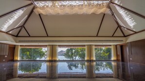 A spacious indoor pool area with a clear view of a lake and mountains in the background. - Tree of Life Amara Resorts & Spa Udaipur (Udaipur)