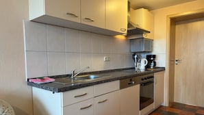 A compact kitchen with white cabinets, a stainless steel sink, and a coffee maker. - Gemütlicher Aufenthalt am Wieker Hafen (Wiek auf Rügen)