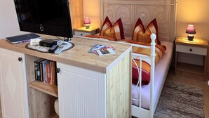 A bedroom with a bed, a desk with a computer, a TV, and two bedside lamps. - Gemütlicher Aufenthalt am Wieker Hafen (Wiek auf Rügen)