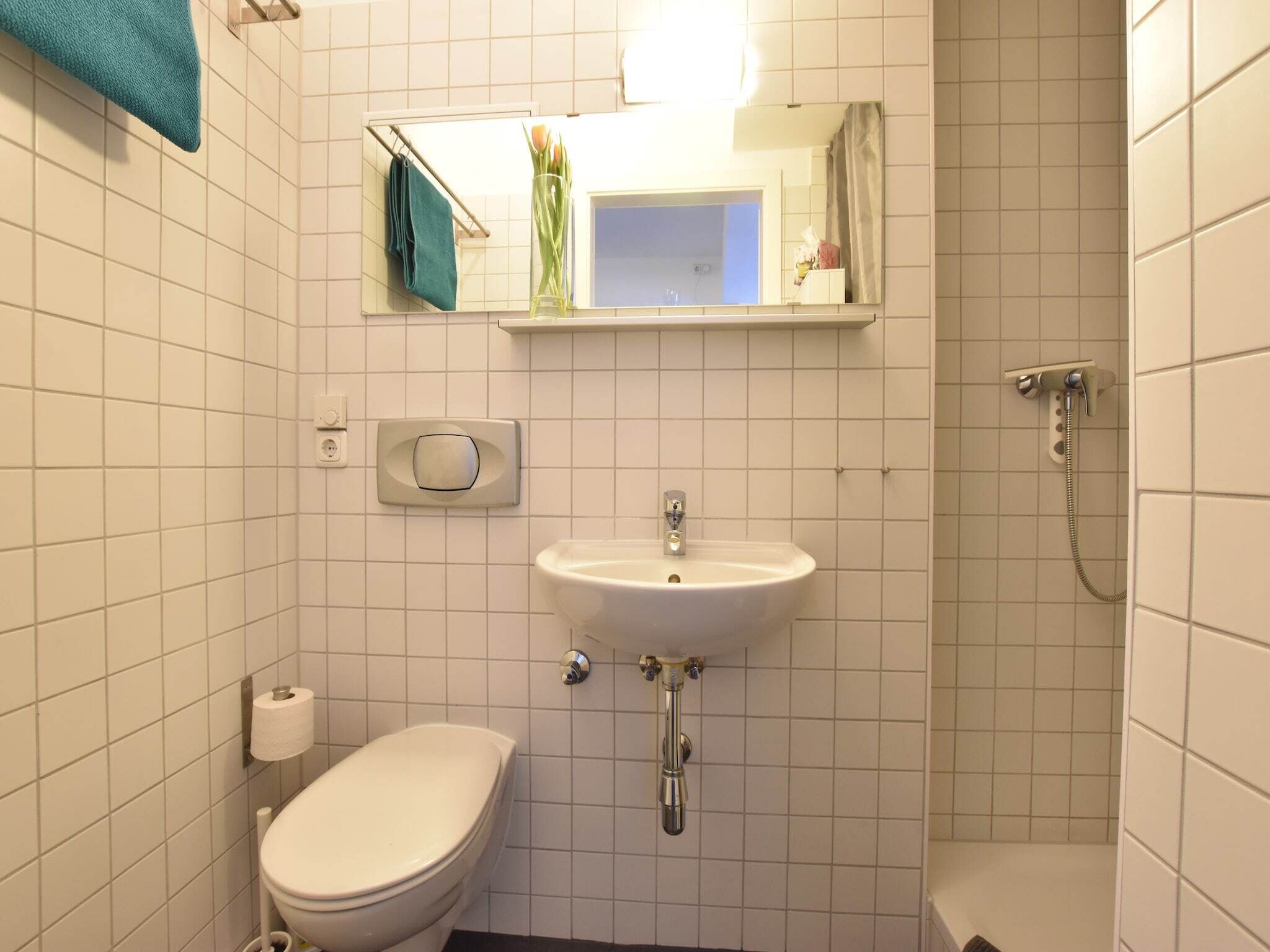 A small bathroom with a toilet, sink, and shower.