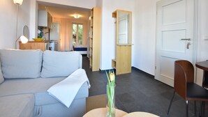 A modern living room with a sofa, a dining table, a chair, and a vase with flowers. - Wohnung in Wismar mit Garten (Wismar)
