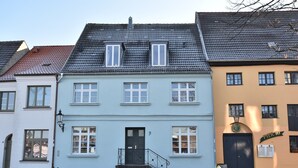 A traditional European building with a light blue facade, a black door, and a small staircase leading to the entrance. - Wohnung in Wismar mit Garten (Wismar)