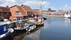 A harbor with boats docked, a flag on a pole, and buildings with red roofs. - Wohnung in Wismar mit Garten (Wismar)